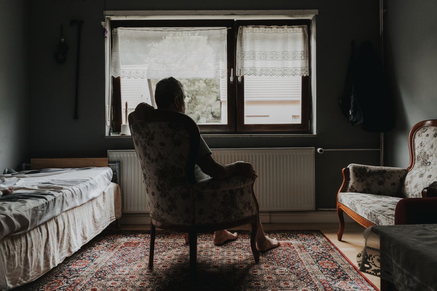 eine Person sitzt in einem dunklen Raum vor einem Fenster (c) Stella Costa eine Person sitzt in einem dunklen Raum vor einem Fenster